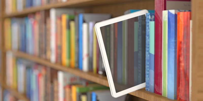 A tablet sitting in a row of books.